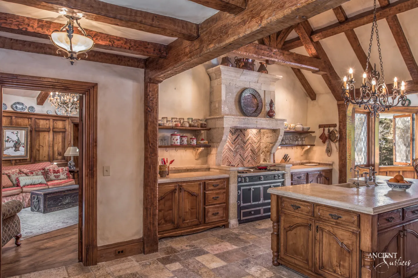 Timber framed kitchen with a range set inside a pale limestone hood of squared blocks with a moulded cornice and curved corbels, a herringbone brick back panel and pale stone counters
