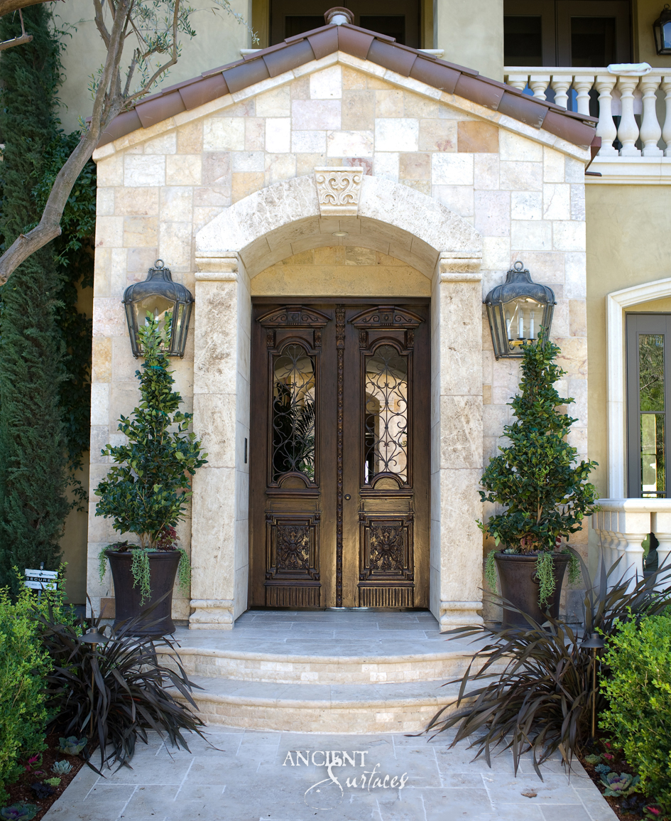 Entry portico clad in cream and honey limestone, with an arched limestone door surround, carved keystone and curved limestone steps